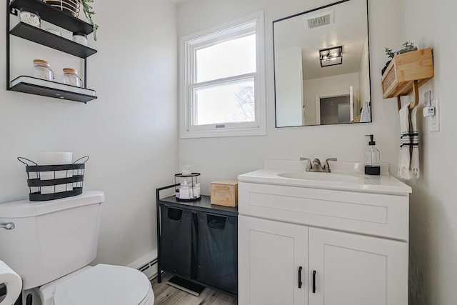 bathroom featuring vanity, toilet, wood-type flooring, and a baseboard heating unit