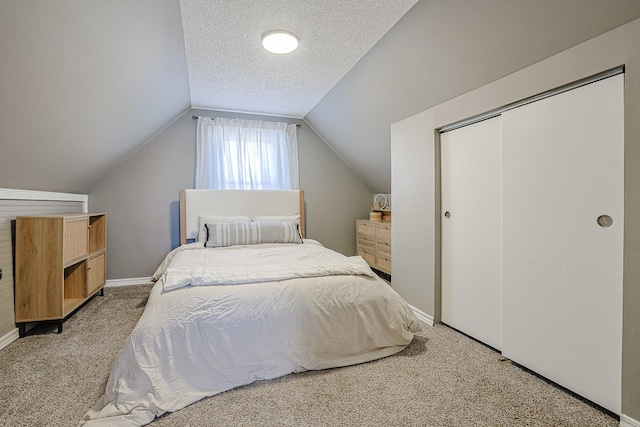 bedroom with lofted ceiling, a closet, a textured ceiling, and carpet flooring