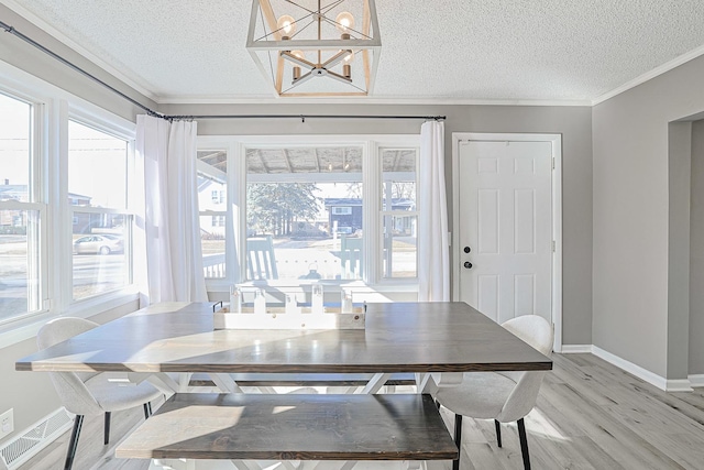 dining space featuring crown molding, hardwood / wood-style floors, a textured ceiling, and a notable chandelier