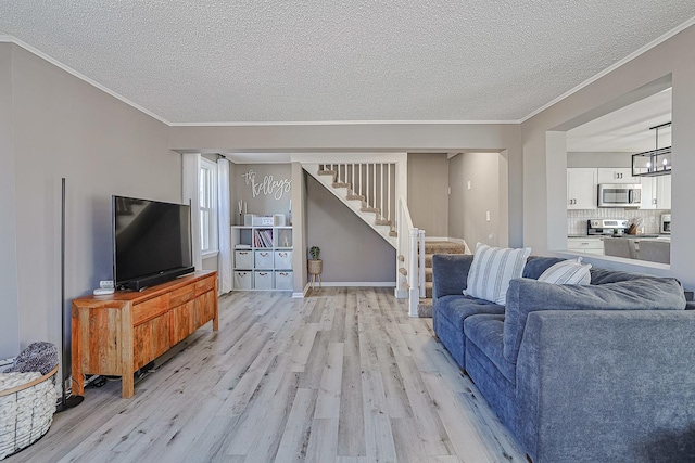 living room featuring crown molding, light hardwood / wood-style floors, and a textured ceiling