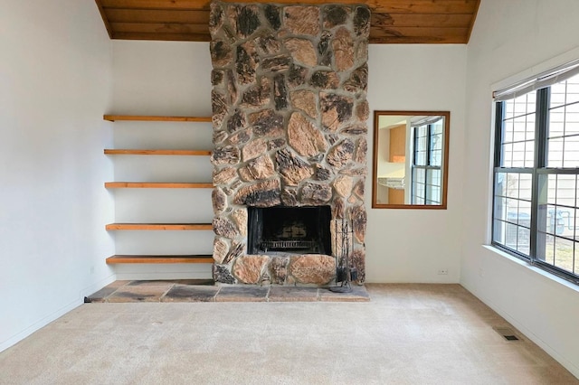 unfurnished living room with lofted ceiling, wood ceiling, a stone fireplace, and carpet