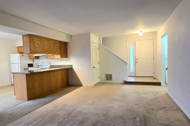 kitchen with white appliances, light colored carpet, and kitchen peninsula