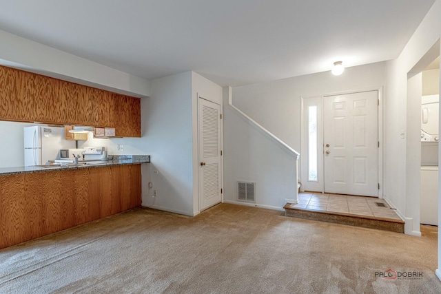 kitchen featuring white refrigerator, light carpet, and electric range