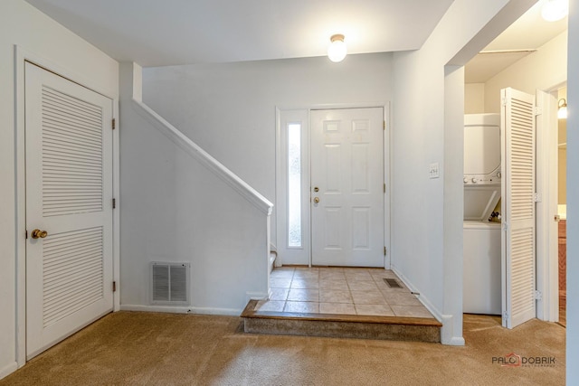 carpeted foyer entrance with stacked washer and dryer