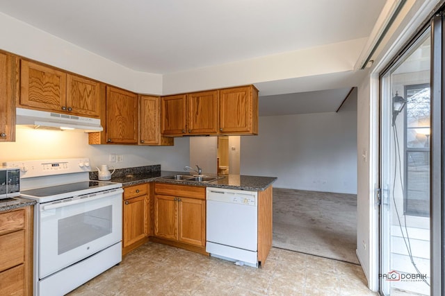 kitchen featuring sink, dark stone counters, light colored carpet, kitchen peninsula, and white appliances