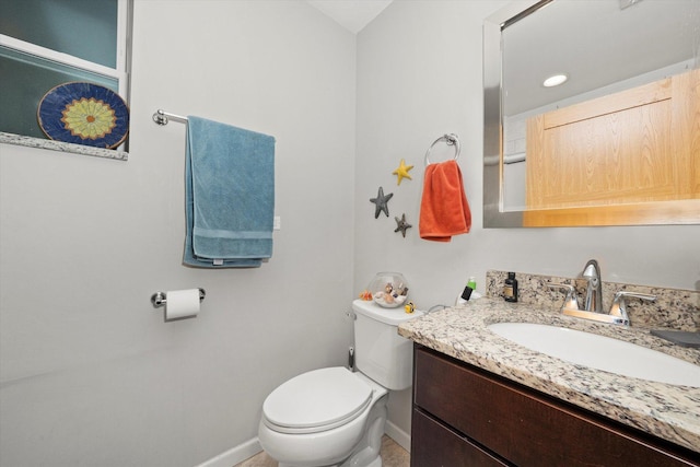 bathroom with toilet, vanity, and baseboards