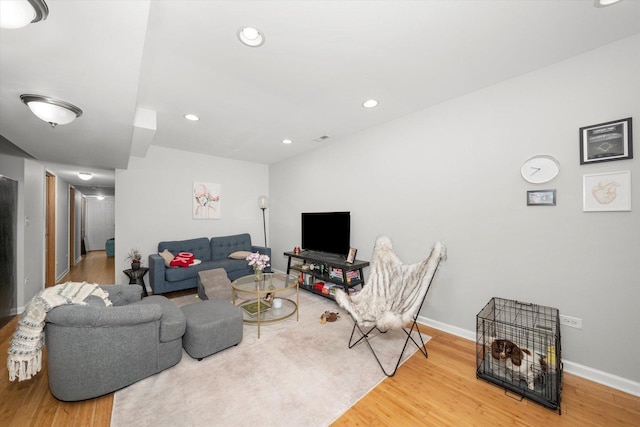 living area with baseboards, wood finished floors, and recessed lighting