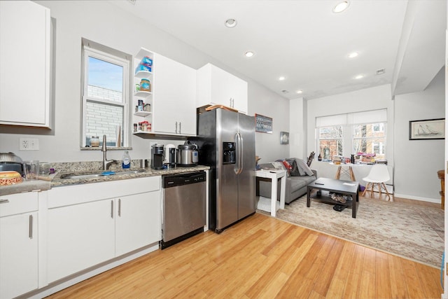 kitchen featuring dark stone countertops, stainless steel appliances, white cabinetry, open shelves, and a sink