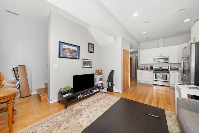 living room with light wood-type flooring, visible vents, and recessed lighting