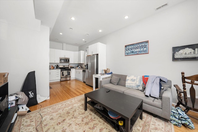 living area with recessed lighting, visible vents, and light wood-style floors