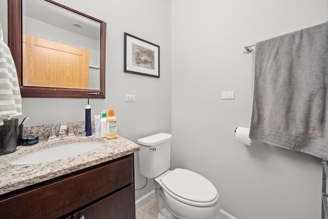 bathroom featuring toilet, baseboards, and vanity