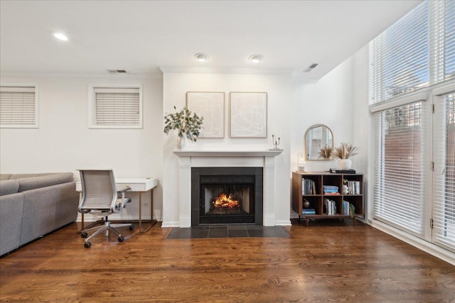 living room featuring a fireplace, crown molding, and dark wood-type flooring