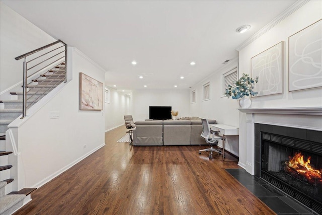 living room featuring a tiled fireplace, crown molding, and dark hardwood / wood-style floors