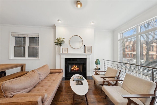 living room with a tiled fireplace, dark hardwood / wood-style flooring, and ornamental molding