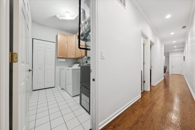 clothes washing area featuring cabinets, ornamental molding, light tile patterned floors, and independent washer and dryer