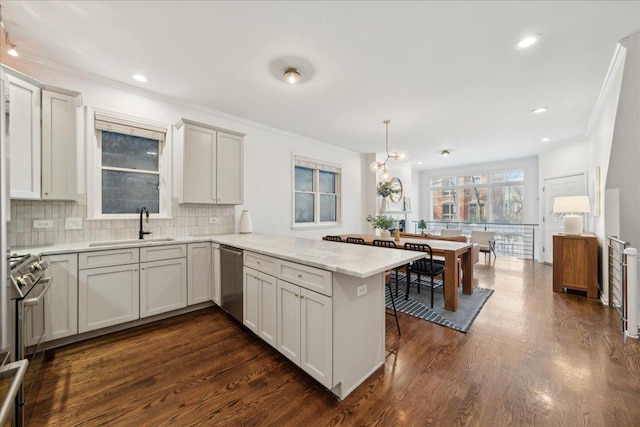 kitchen featuring sink, dark wood-type flooring, hanging light fixtures, stainless steel appliances, and kitchen peninsula