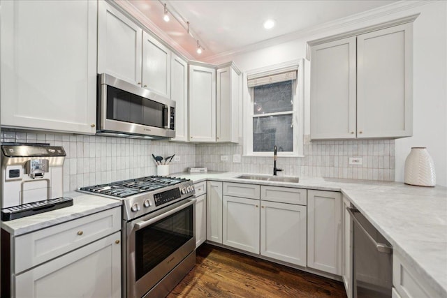 kitchen featuring appliances with stainless steel finishes, sink, backsplash, white cabinets, and light stone counters