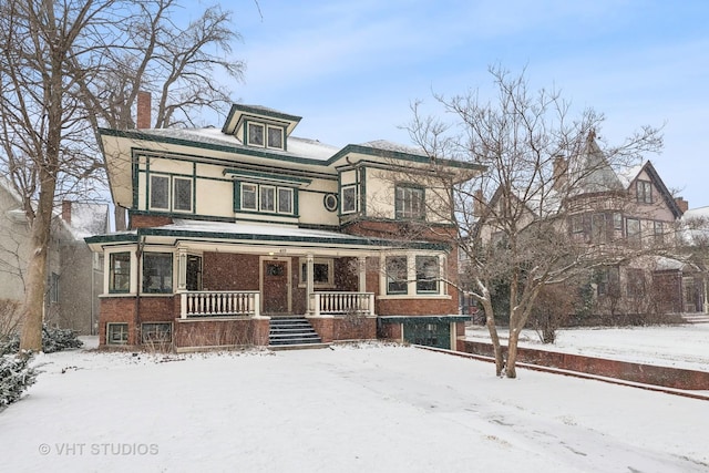 view of front facade with a porch, brick siding, and a chimney