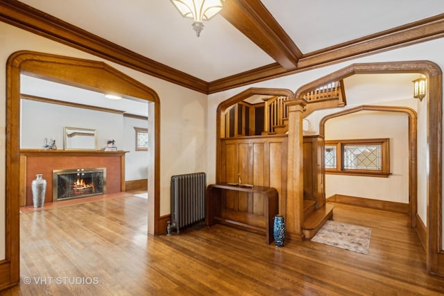 interior space featuring radiator, crown molding, wood finished floors, and a glass covered fireplace