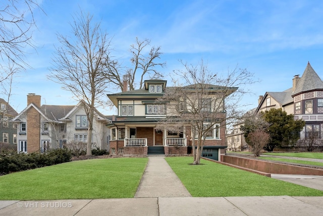 american foursquare style home with covered porch, brick siding, a front yard, and a balcony