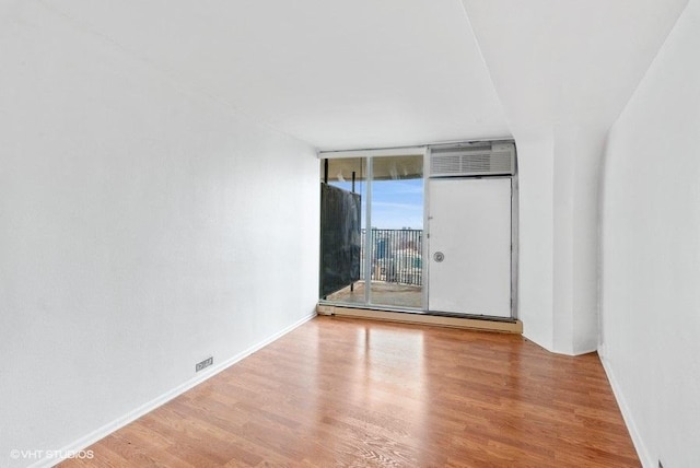 empty room featuring expansive windows and hardwood / wood-style floors