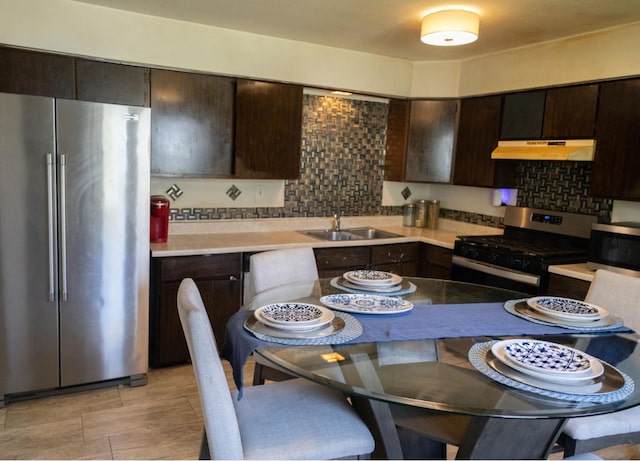 kitchen with dark brown cabinetry, appliances with stainless steel finishes, sink, and decorative backsplash