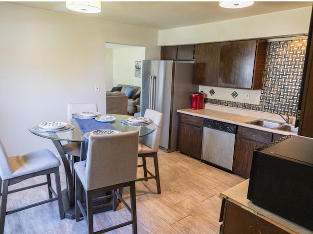 kitchen featuring stainless steel appliances, sink, dark brown cabinetry, and light hardwood / wood-style floors