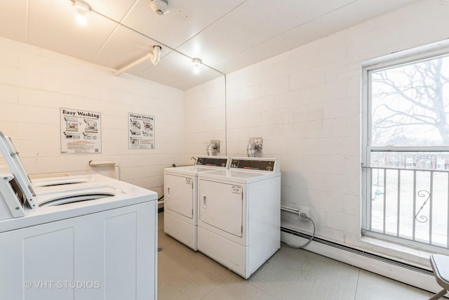 community laundry room featuring washer and dryer, concrete block wall, and baseboard heating