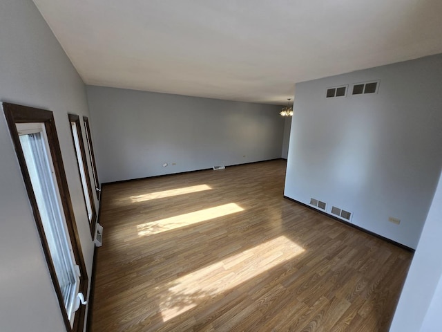 unfurnished room featuring a notable chandelier and dark hardwood / wood-style flooring