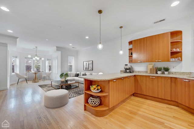 kitchen with light wood finished floors, visible vents, light stone counters, decorative light fixtures, and open shelves