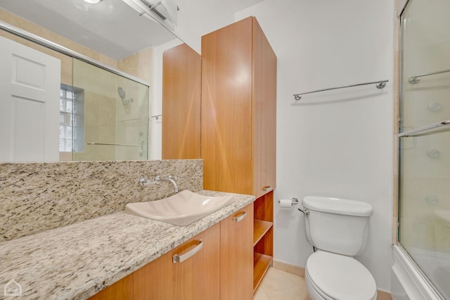 full bathroom featuring baseboards, toilet, tile patterned floors, combined bath / shower with glass door, and vanity