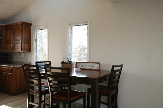 dining area featuring lofted ceiling and light wood-type flooring