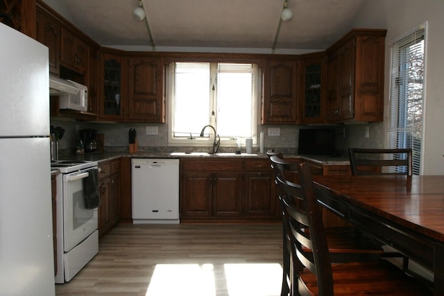 kitchen featuring lofted ceiling, sink, tasteful backsplash, light hardwood / wood-style flooring, and white appliances