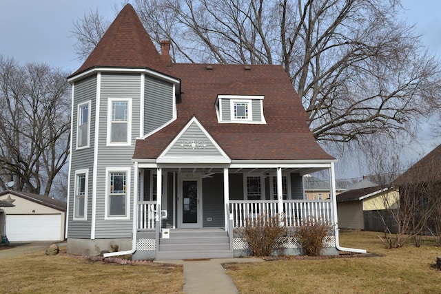 victorian home with a garage, an outbuilding, covered porch, and a front lawn