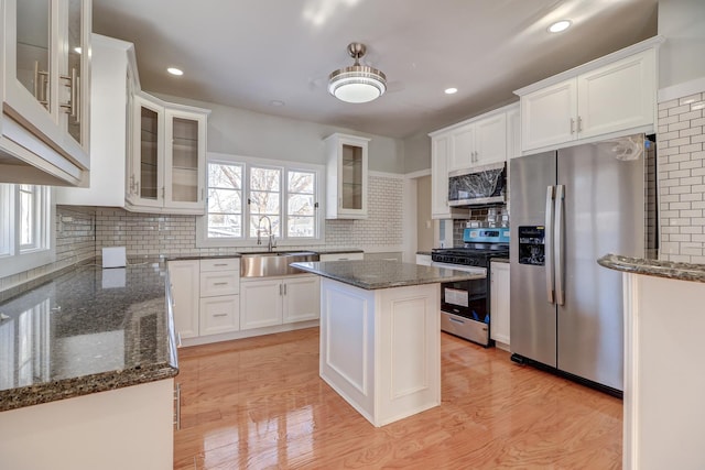 kitchen featuring stainless steel appliances, dark stone counters, white cabinets, and a kitchen island