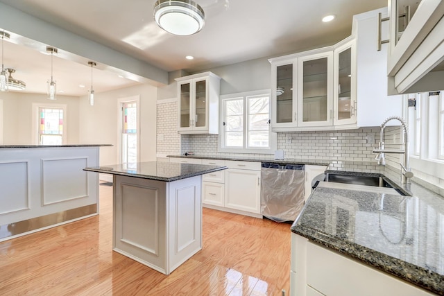 kitchen with white cabinetry, dishwasher, a center island, and dark stone countertops