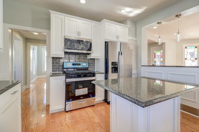 kitchen with a kitchen island, white cabinetry, decorative backsplash, stainless steel appliances, and light hardwood / wood-style flooring