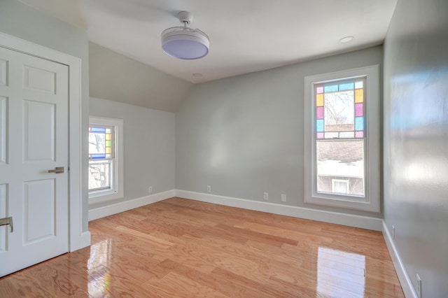 unfurnished room with lofted ceiling, a healthy amount of sunlight, and light wood-type flooring