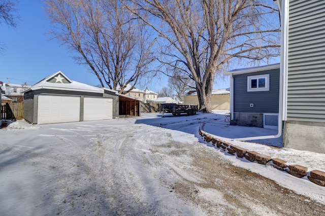 yard layered in snow featuring an outbuilding and a garage