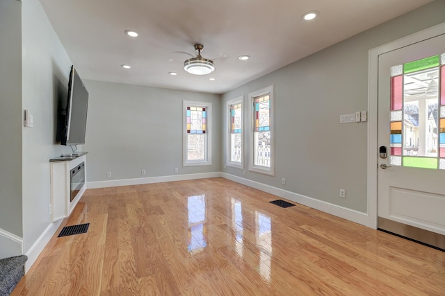 unfurnished living room with ceiling fan and light wood-type flooring