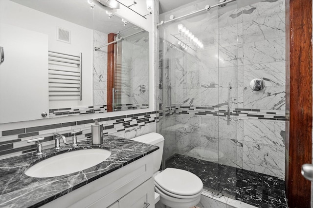 bathroom featuring a tile shower, vanity, tasteful backsplash, and toilet