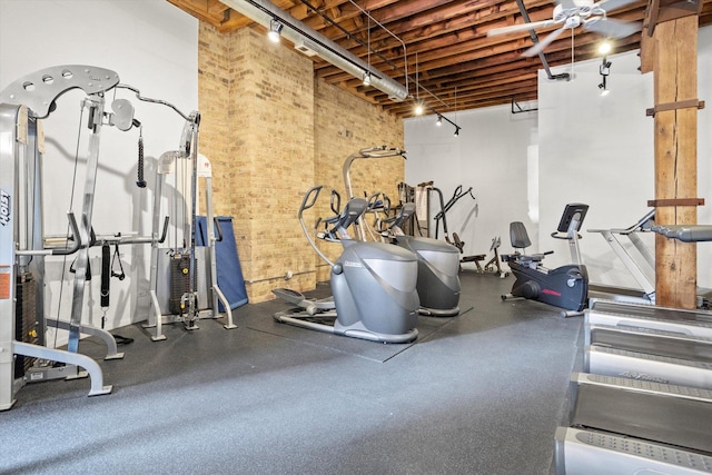 exercise room featuring brick wall and a towering ceiling