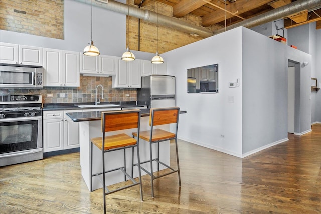 kitchen with white cabinetry, a towering ceiling, appliances with stainless steel finishes, and sink