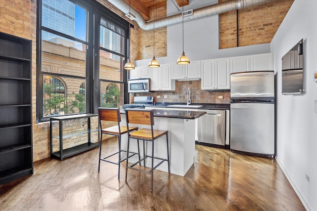 kitchen with sink, a high ceiling, white cabinets, and appliances with stainless steel finishes