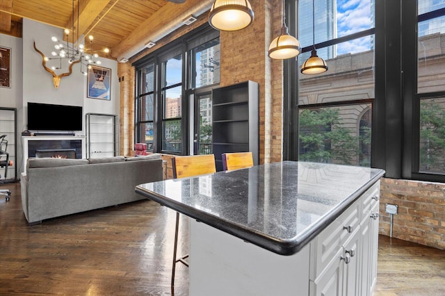 kitchen featuring a kitchen bar, decorative light fixtures, dark stone countertops, a kitchen island, and white cabinets