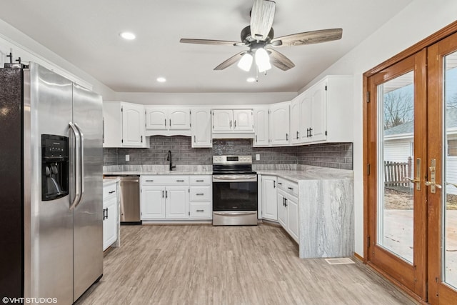 kitchen with stainless steel appliances, white cabinets, and light wood-style floors