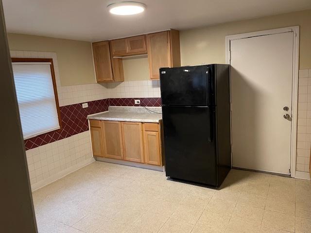 kitchen featuring black fridge and tile walls