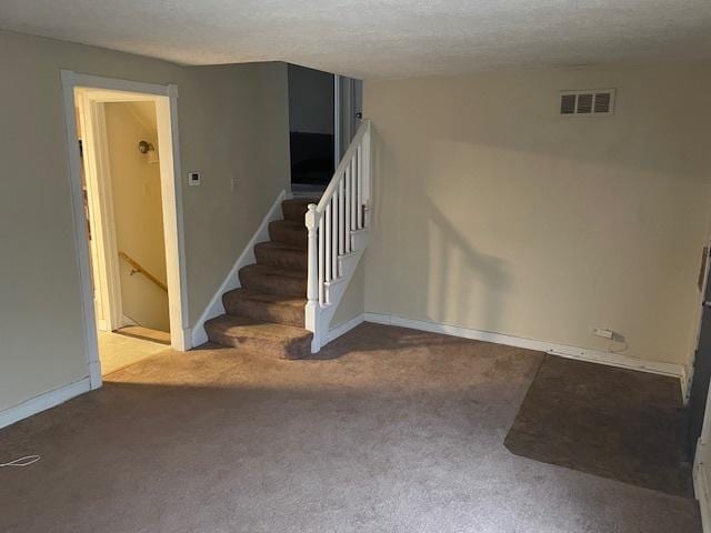 stairway featuring carpet flooring and a textured ceiling