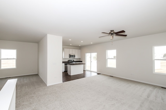 unfurnished living room with ceiling fan and carpet