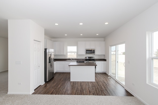 kitchen with a healthy amount of sunlight, appliances with stainless steel finishes, a kitchen island, and white cabinets